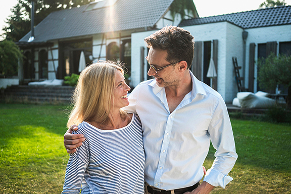 Couple standing in front of a home on the lawn