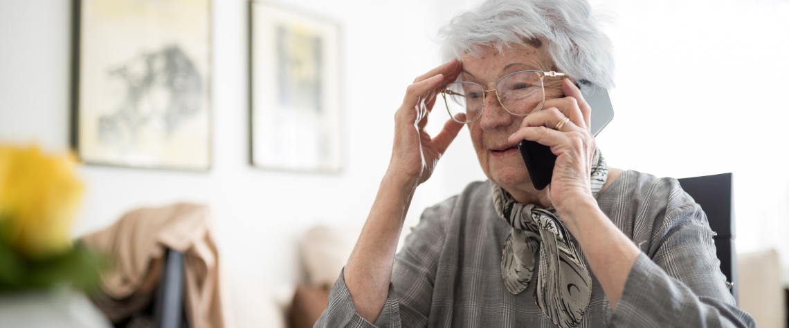 Sad and lonely senior gray-haired Caucasian woman talking on the mobile phone, receiving bad news. Loneliness and aging concept