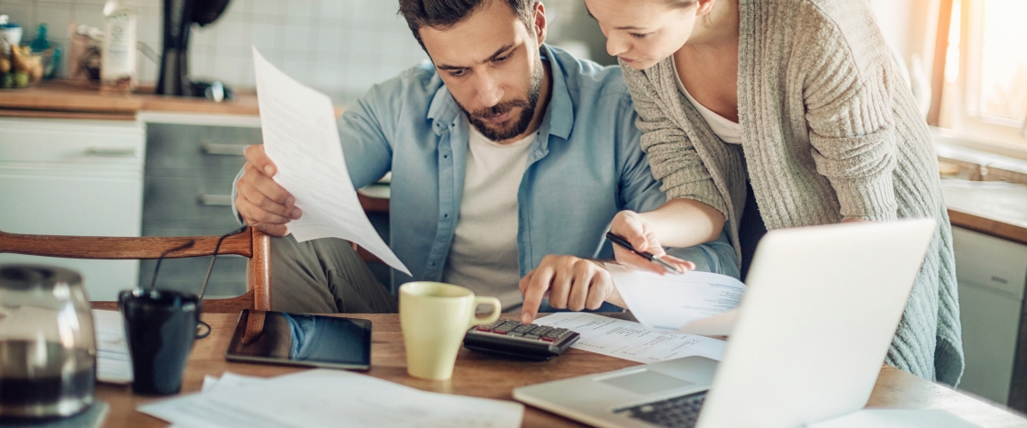 Worried young Caucasian couple going over their bills and home finances in the morning in the kitchen